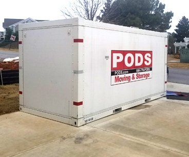 A white pods moving and storage container is parked in a driveway.