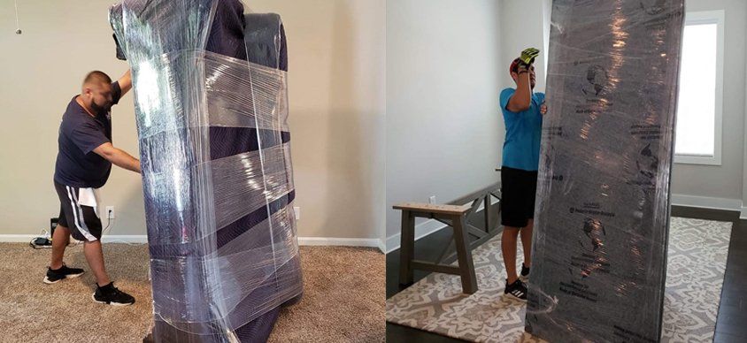A man is wrapping a piece of furniture in plastic wrap.