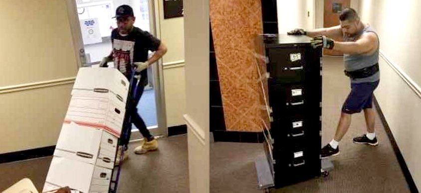 A man is carrying a large box down a hallway.