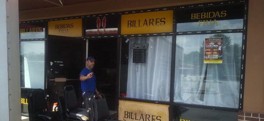 A man on a motorcycle is standing in front of a store.