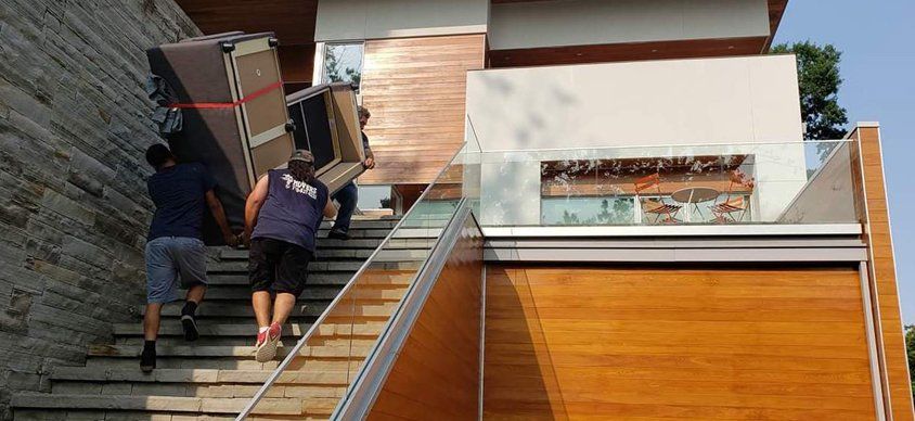 A couple of men are carrying a refrigerator up a set of stairs.