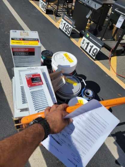 A person is holding a piece of paper in front of a table with boxes and a sign that says $ 119