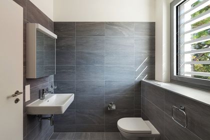 Interior of a modern house, gray bathroom, tiled walls and white ceiling