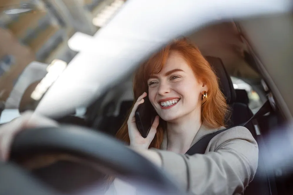 A woman is driving a car and talking on a cell phone.