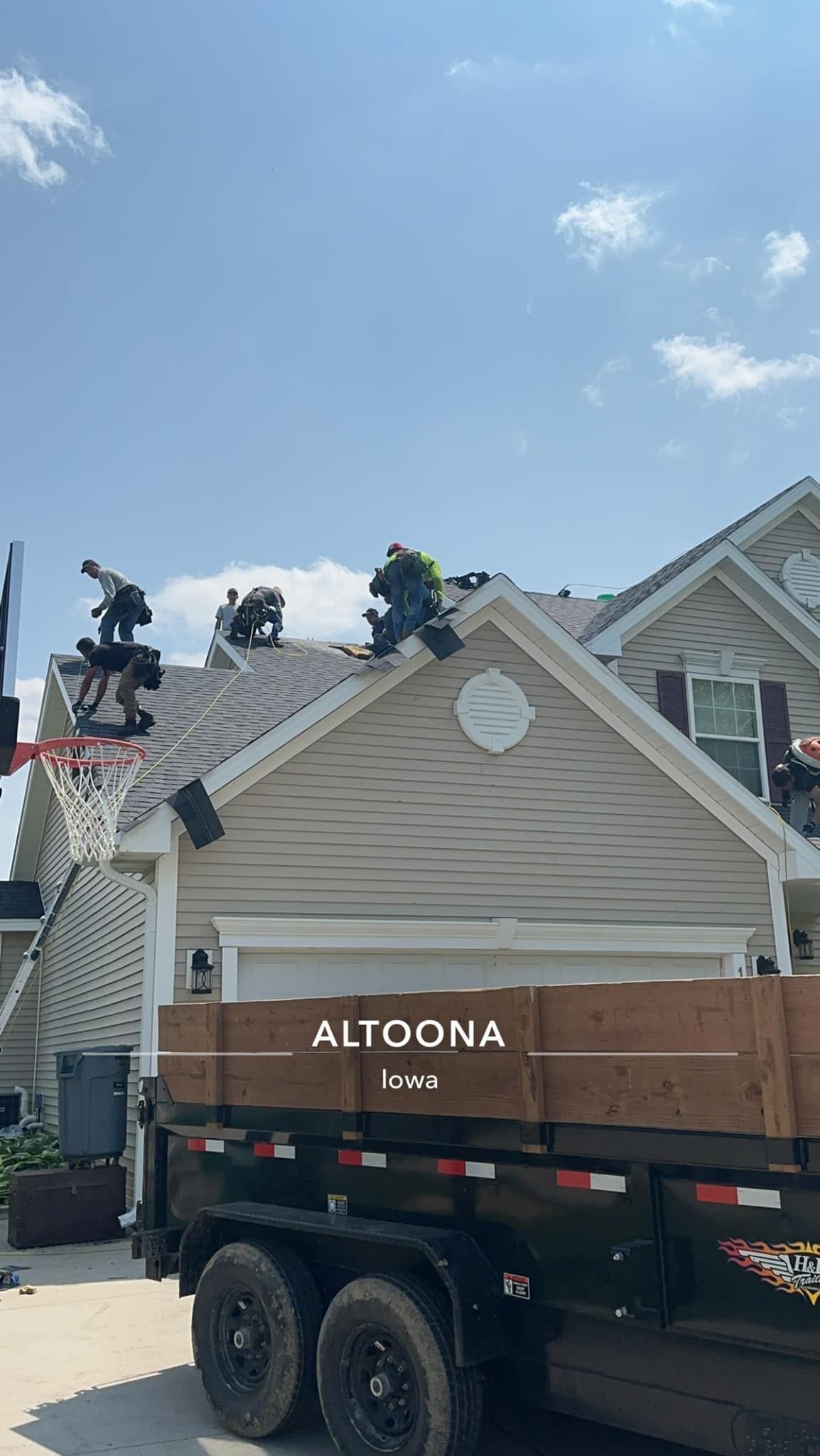 Roofer in overalls and hard hat nailing wooden beams on a rooftop.
