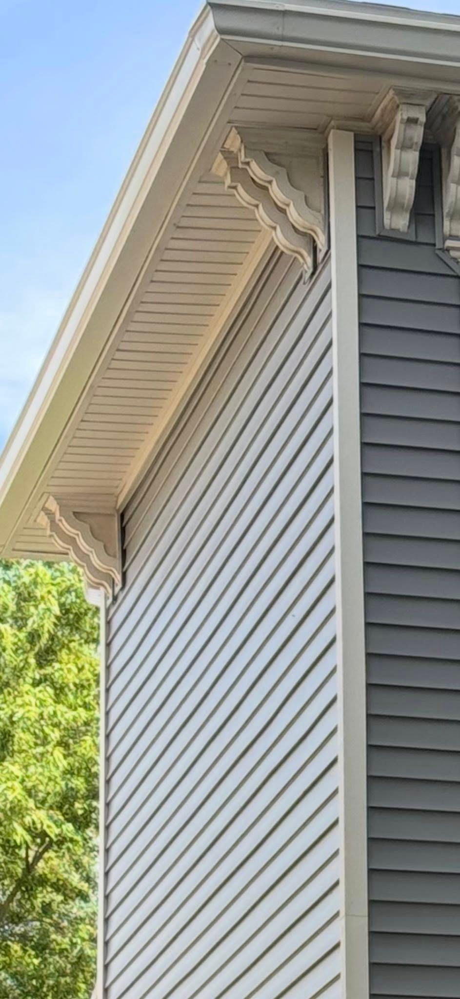 Man installing black gutter on a wooden roof, working outside with sunlight.