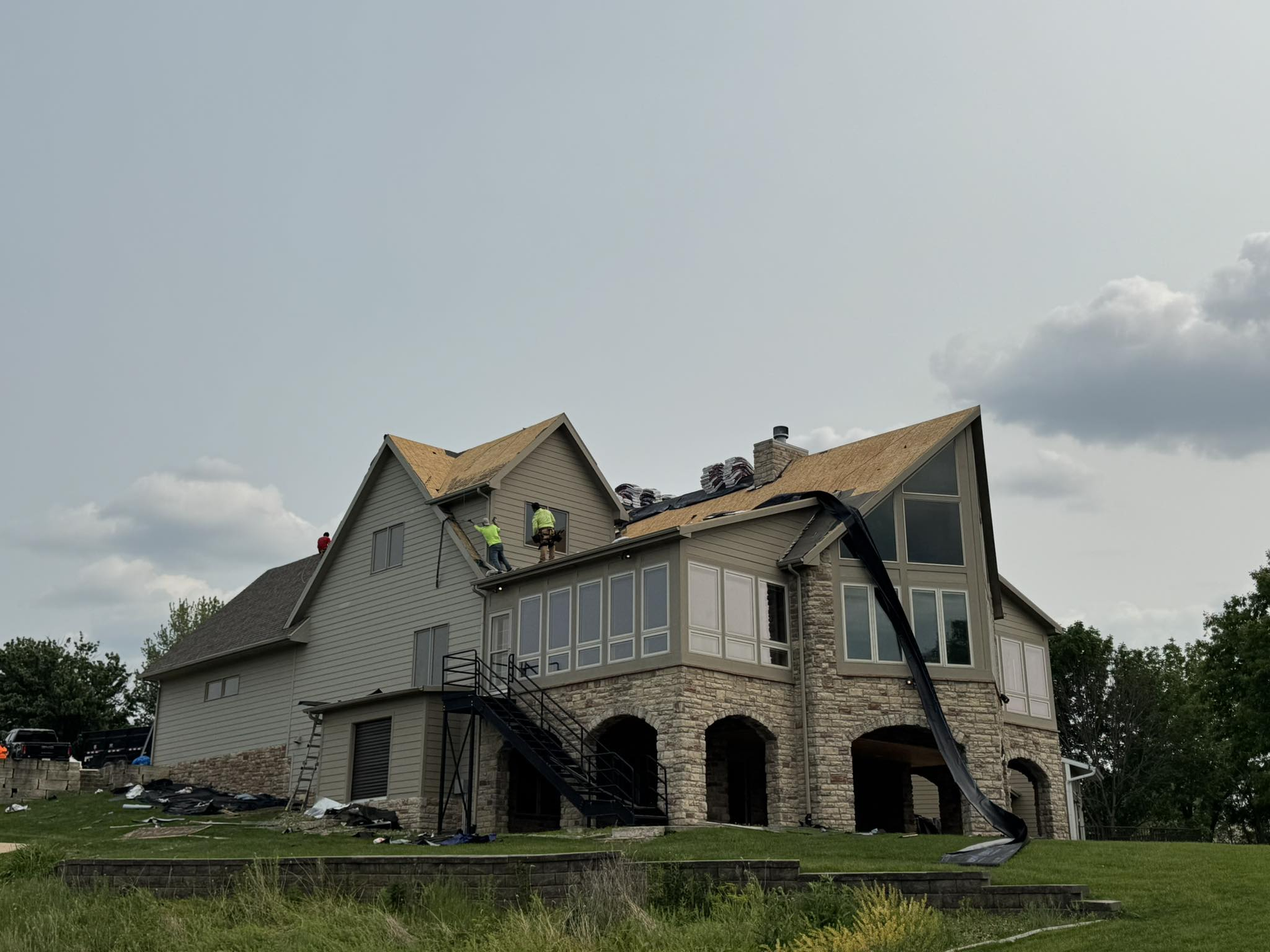 Roofer hammers copper flashing onto a shingled roof, wearing gloves.