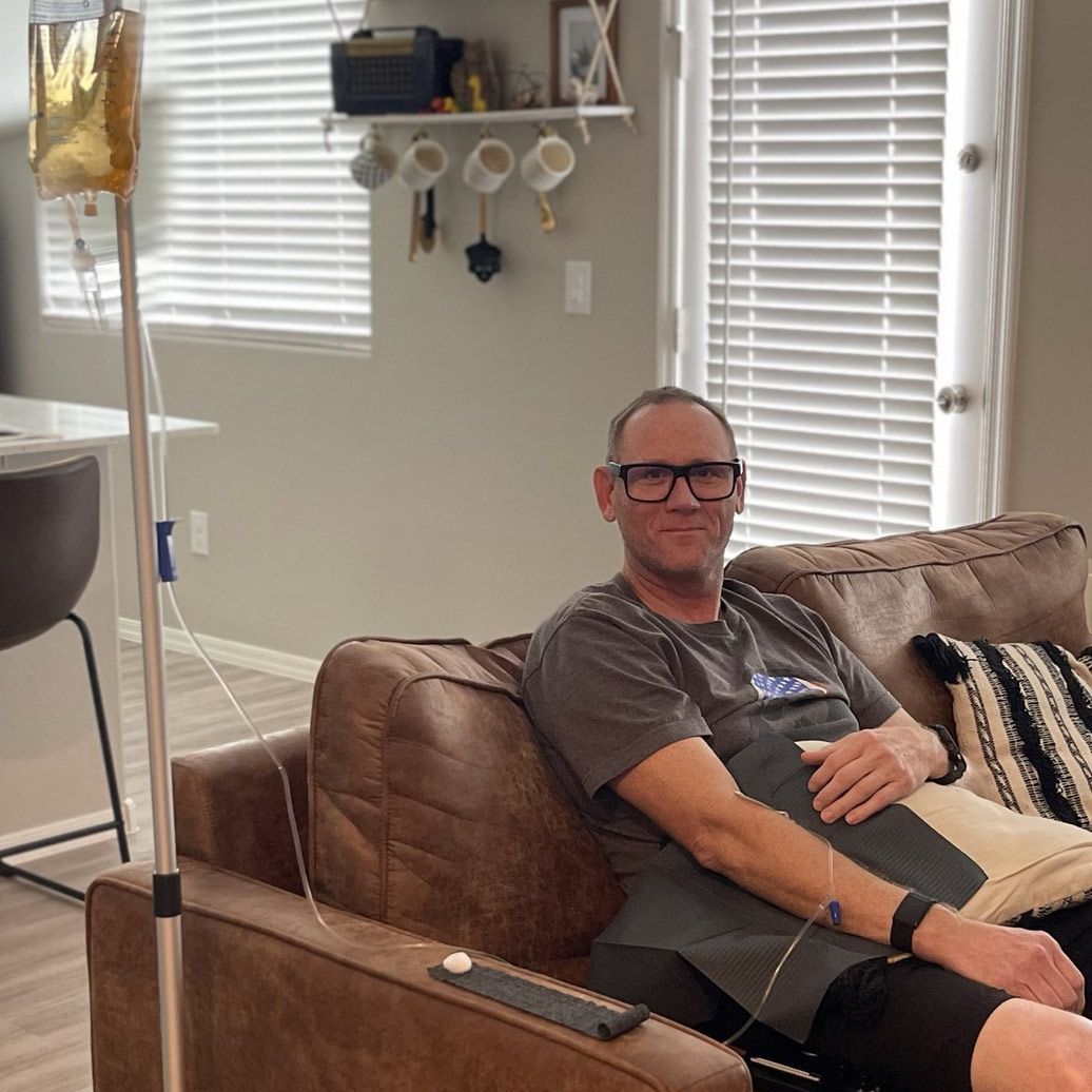 Client receiving a private in-home vitamin IV infusion in his living room, showcasing the convenience of at-home drip therapy