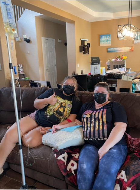 A woman in a red shirt is sitting in front of a sign that says
