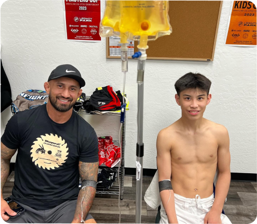 A man and a boy are sitting in front of a sign doing iv therapy
