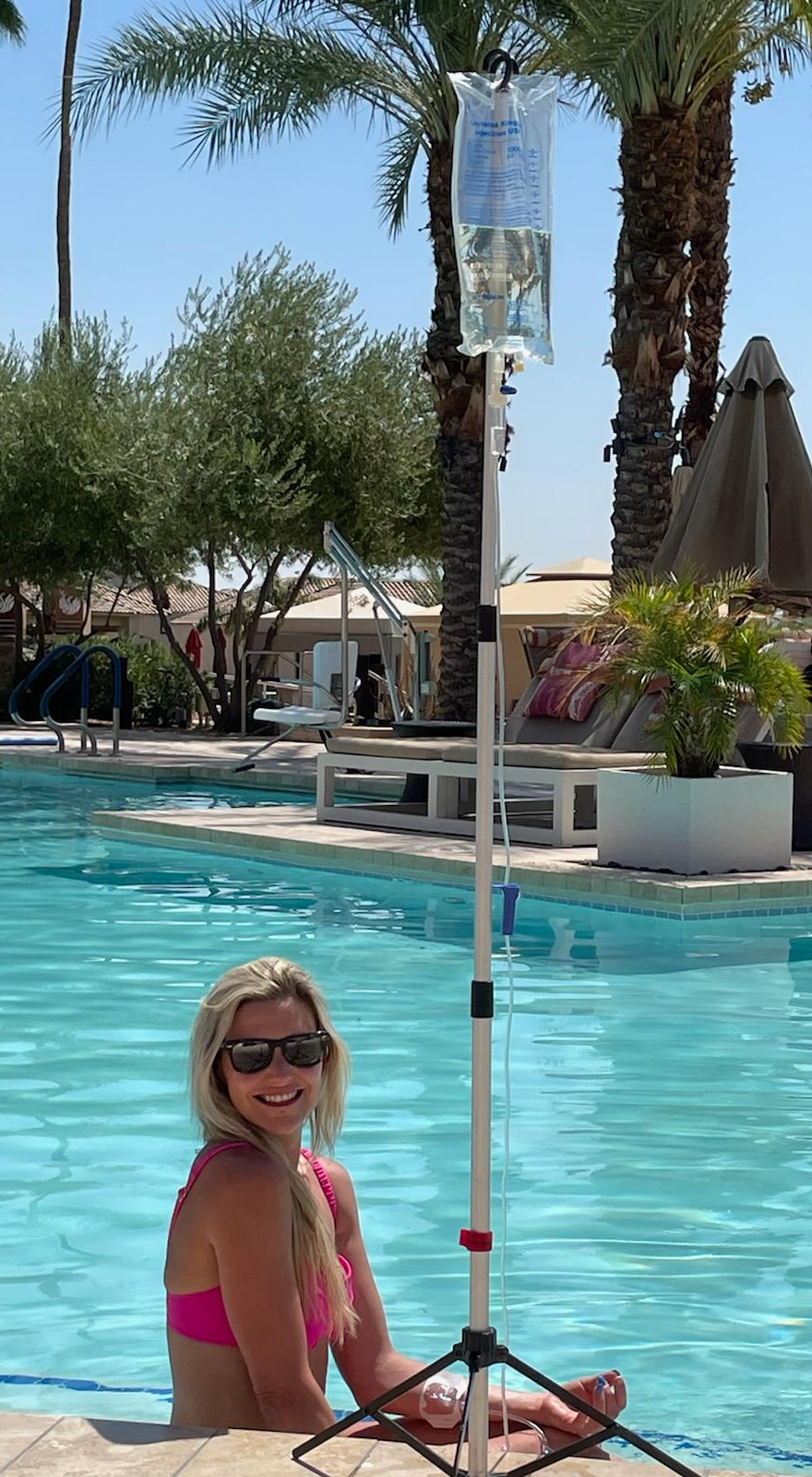 Three people relaxing on a patio, each with an IV bag. They are holding drinks and smiling.