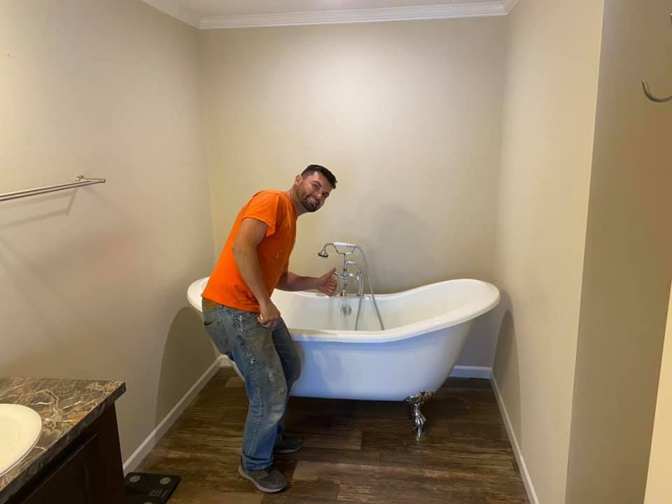 A man in blue overalls is standing in an office with his arms crossed