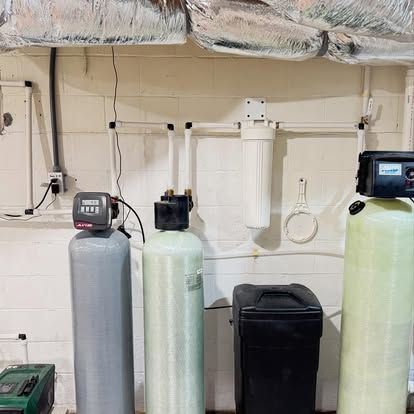Water filtration system with tanks and filters in a basement setting.