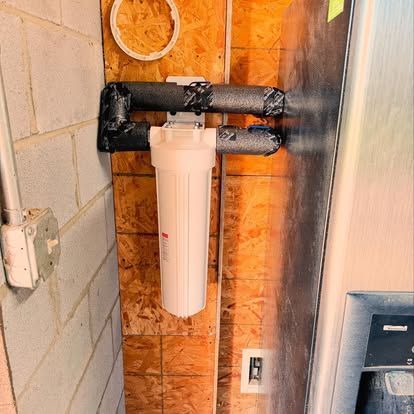Water filter system on wall, with insulated pipes.