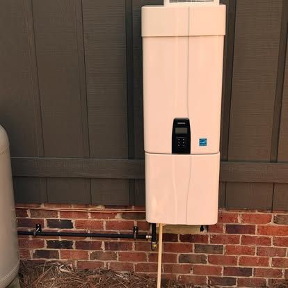 Tan tankless water heater on a brick wall, with a digital display and copper piping.