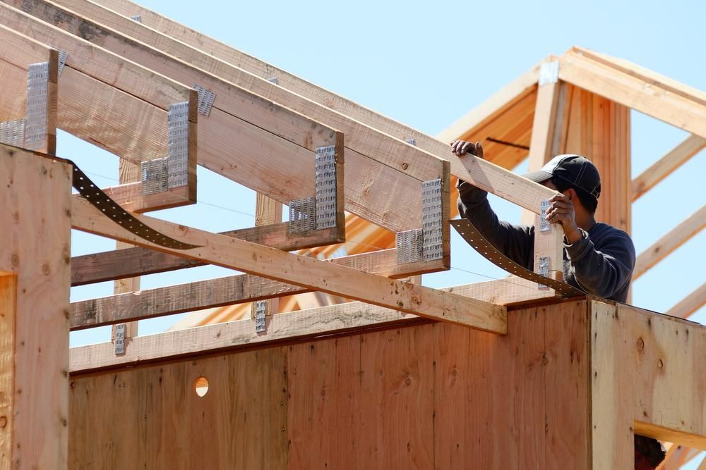 A Man Is Working on The Roof of A Wooden Structure — Trussframe in Maitland, NSW