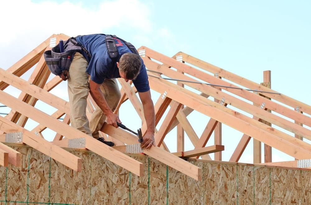 A Man Is Working on The Roof of A House — Trussframe in Narrabri, NSW