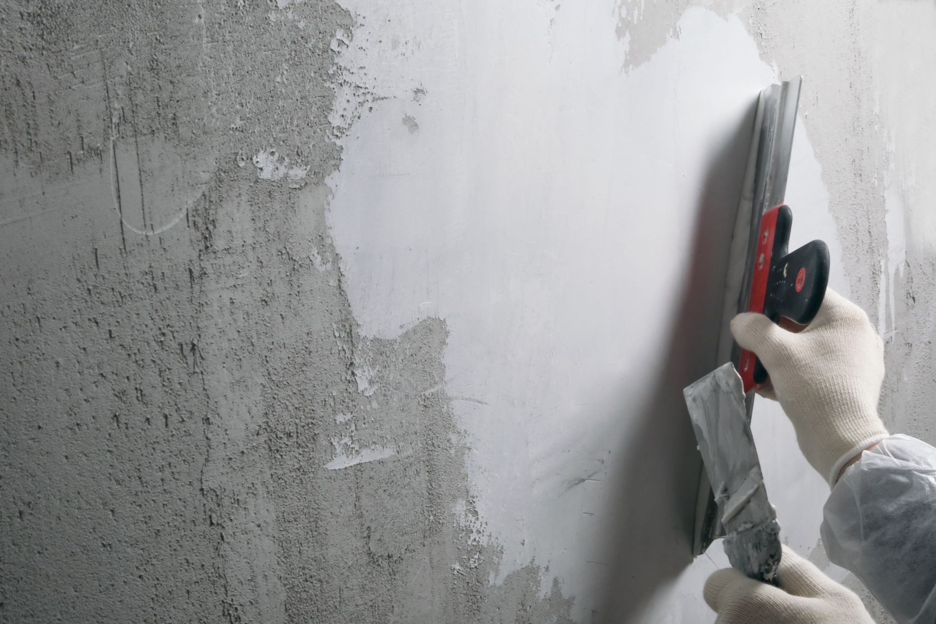 Close-up view of skilled hands meticulously repairing a stucco wall, focusing on the careful mending of concrete with precision.