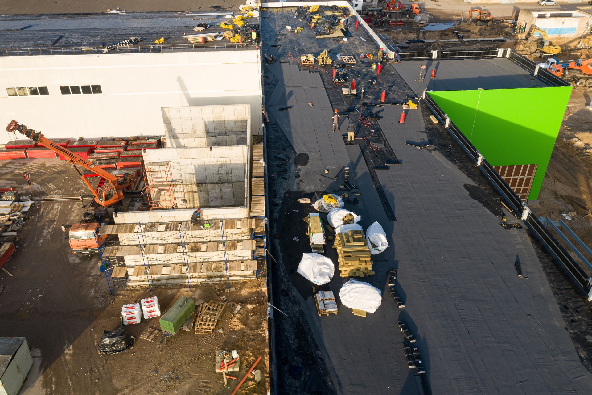 Commercial roof repair with workers and materials on a flat rooftop.