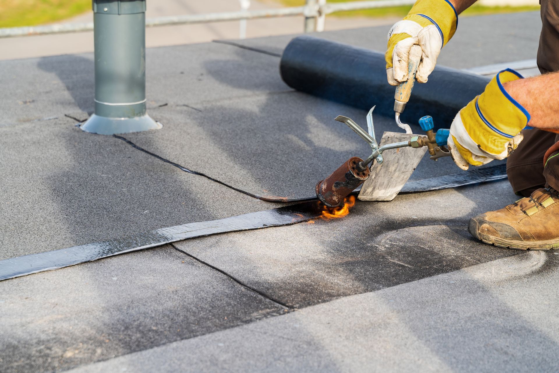 Man heating and melting bitumen roofing on a flat roof. Man heating and melting bitumen roofing on a flat roof.