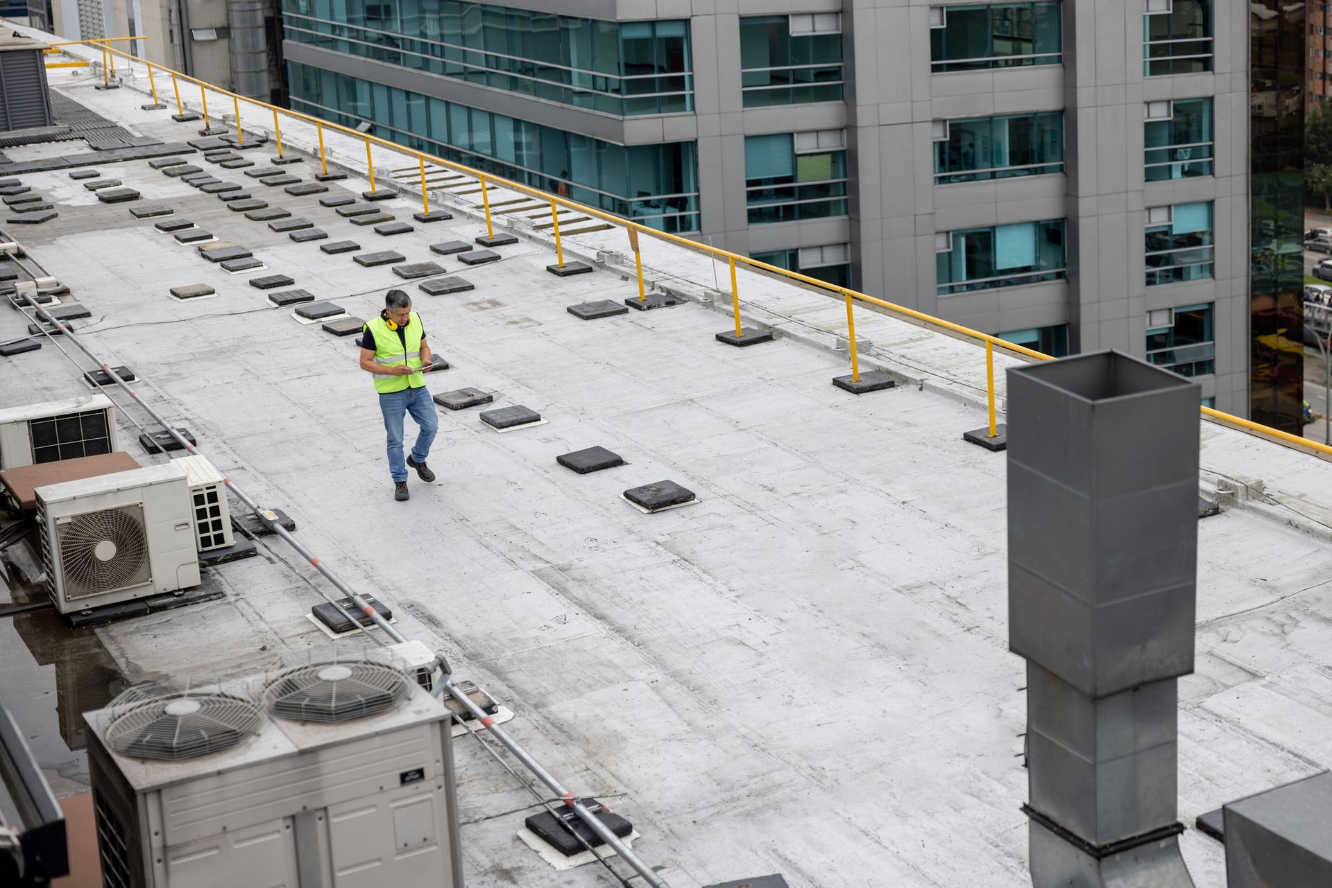 A roofer doing a routine inspection on the rooftop of a building.