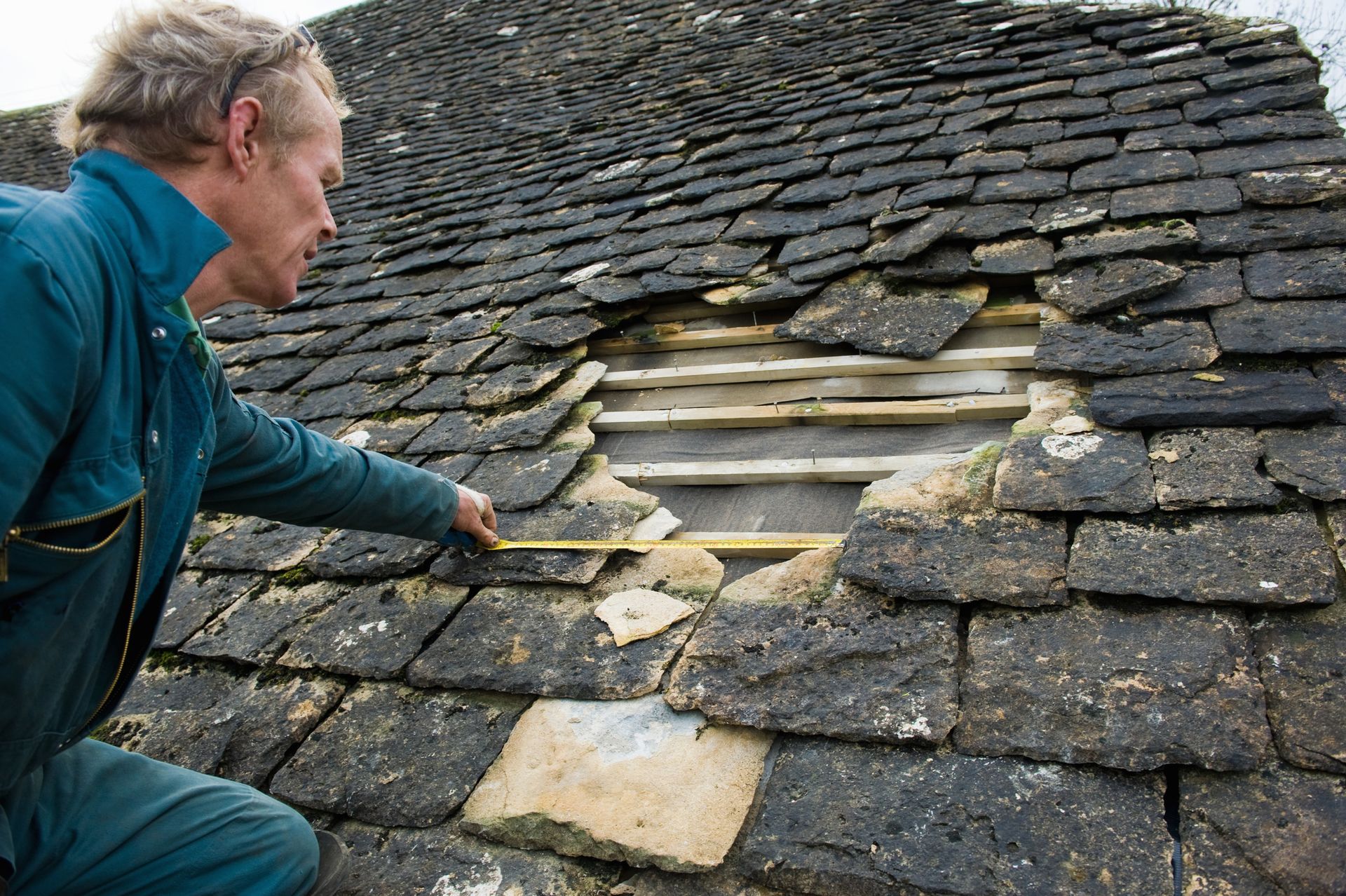 A man is inspecting a damaged roof.
