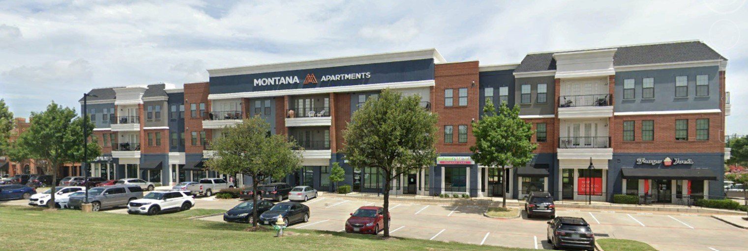 Multi-story commercial building with retail spaces, parking, and green space.