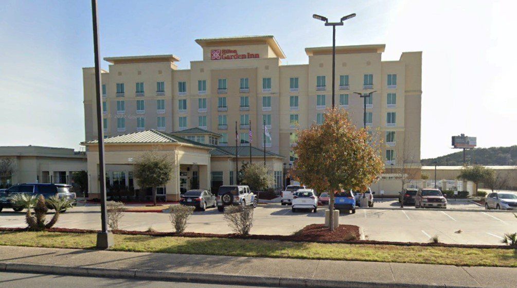 Hilton Garden Inn hotel with cars parked outside on a sunny day.