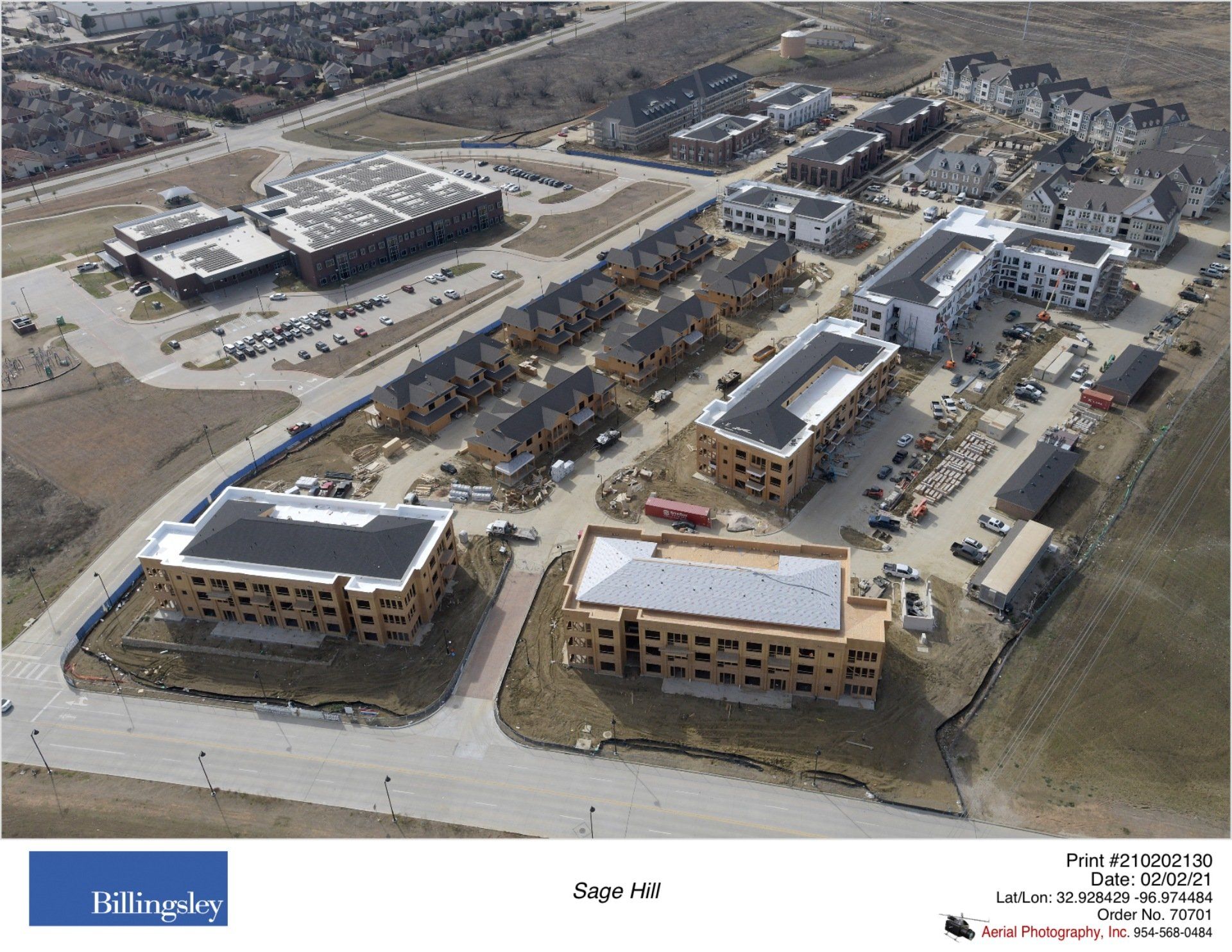 Aerial view of construction site with multiple buildings in various stages, near a large building.