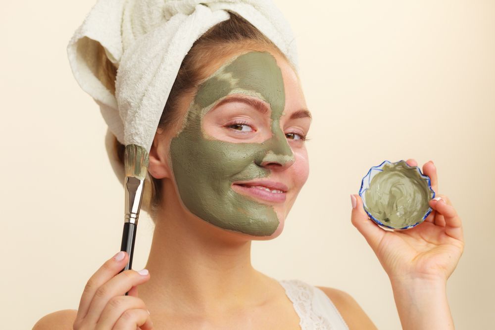 Woman With a Green Facial Mask and Towel on Head Smiles — Skin Haven Aesthetics Whitsundays in Airlie Beach, QLD