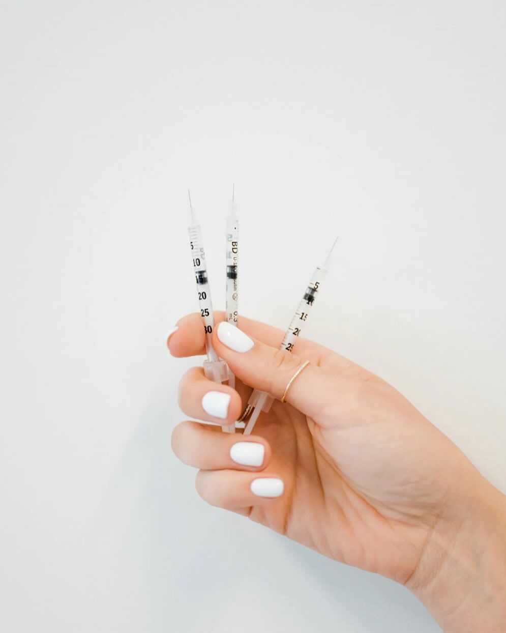 Hand holding three syringes against a white background.— Skin Haven Aesthetics Whitsundays in Airlie Beach, QLD
