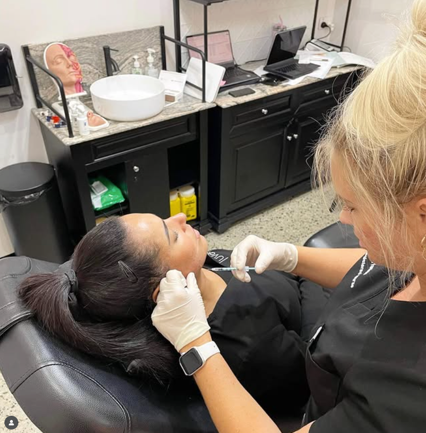 Woman receiving a cosmetic injection near her jaw from a person wearing gloves in a medical setting.— Skin Haven Aesthetics Whitsundays in Airlie Beach, QLD