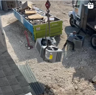 A crane is lifting an air conditioner out of a dumpster