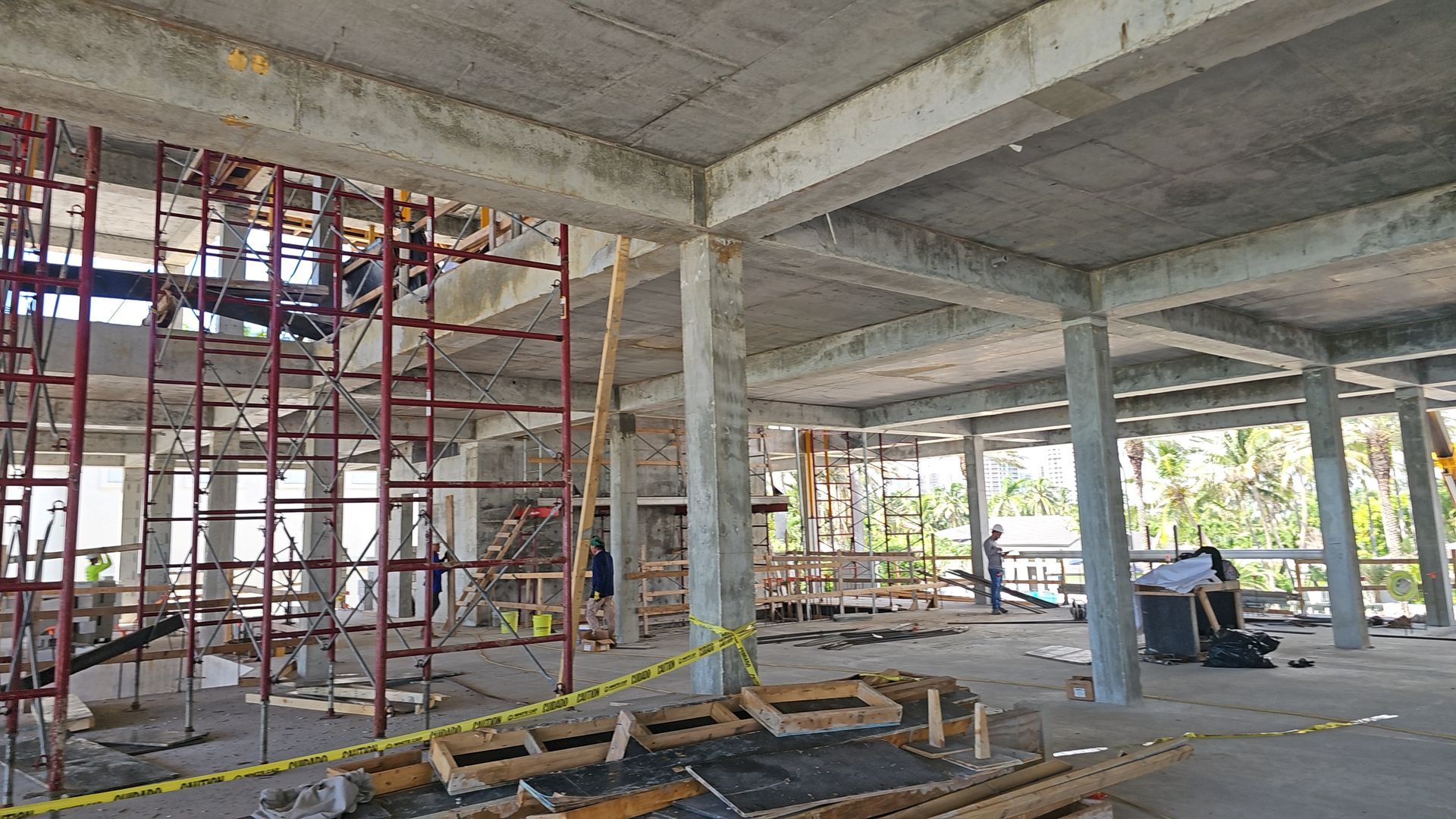 A large building under construction with scaffolding and concrete pillars.