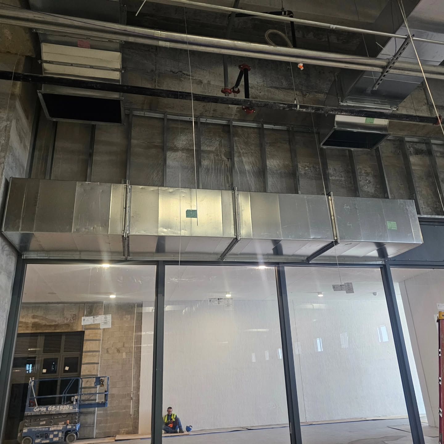 A room with a lot of windows and a metal duct hanging from the ceiling.