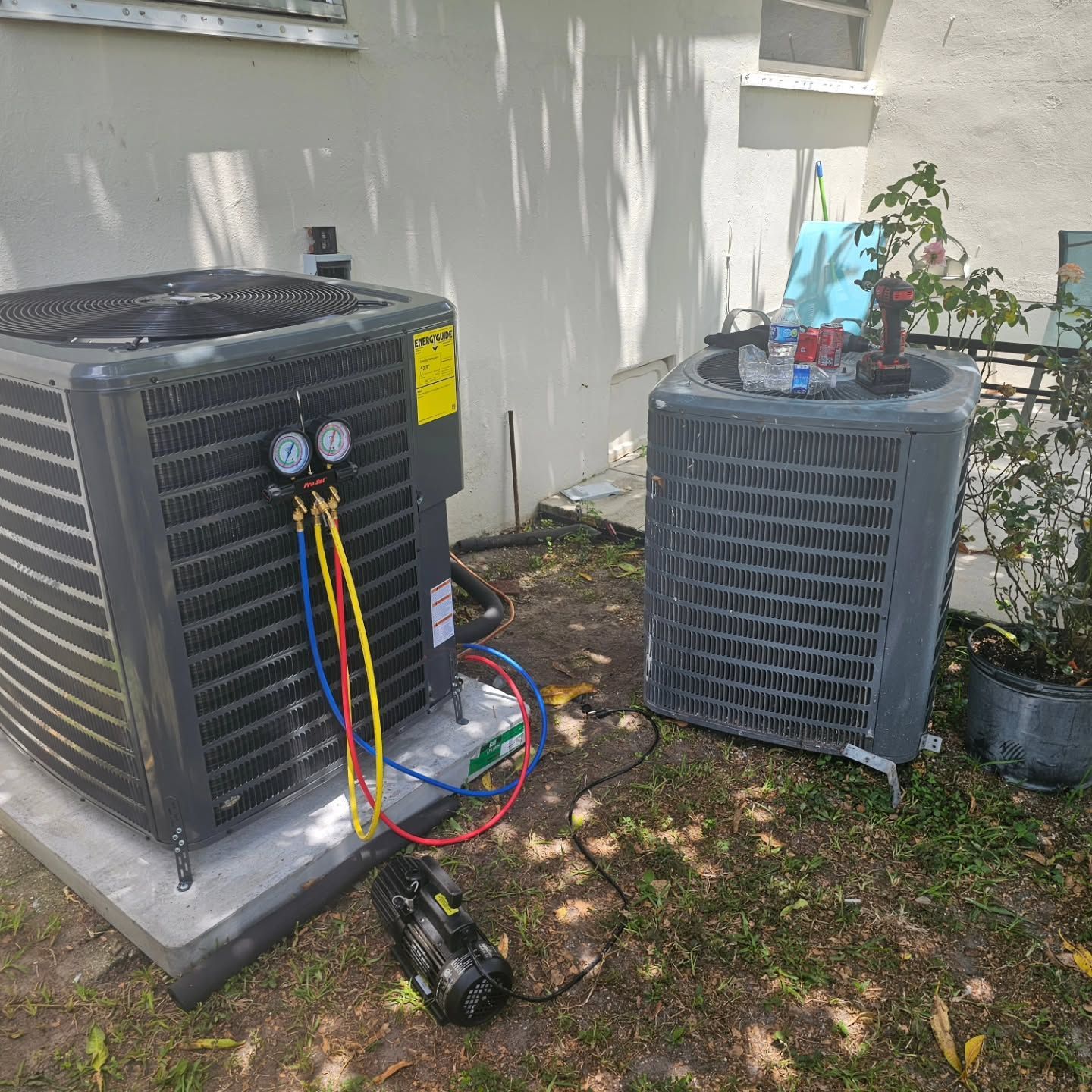 A couple of air conditioners are sitting next to each other in a yard.