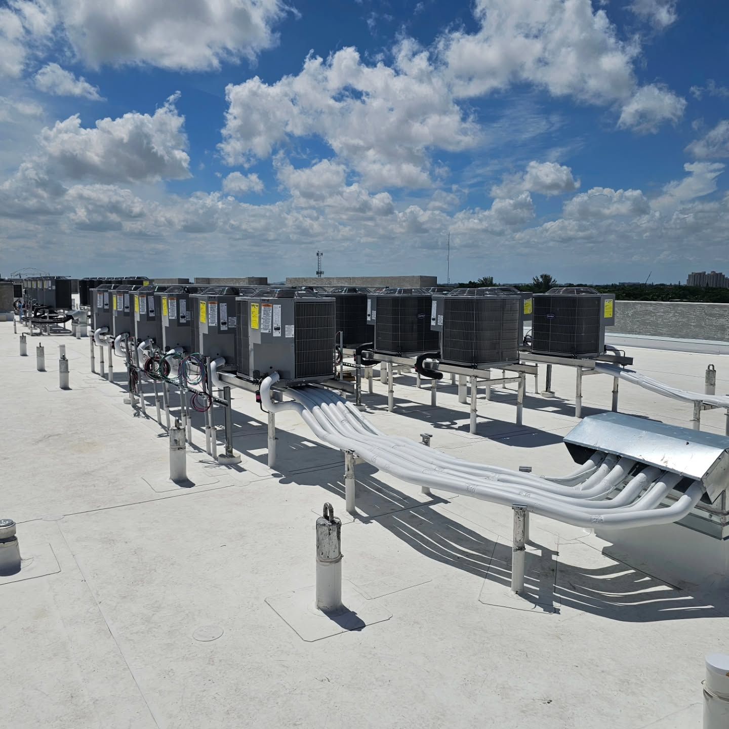 A row of air conditioners are lined up on a white roof