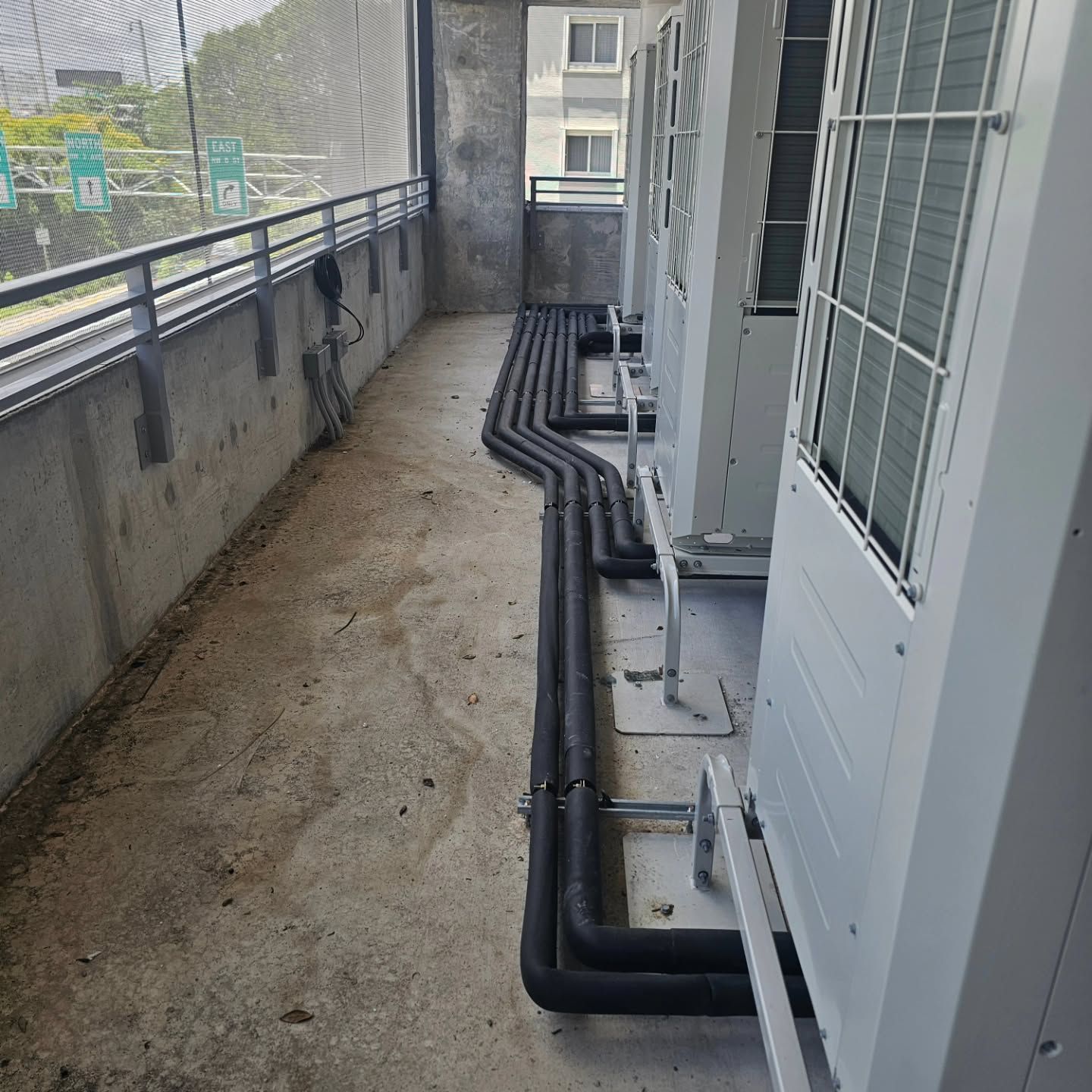 A row of air conditioners are lined up next to each other on a balcony.