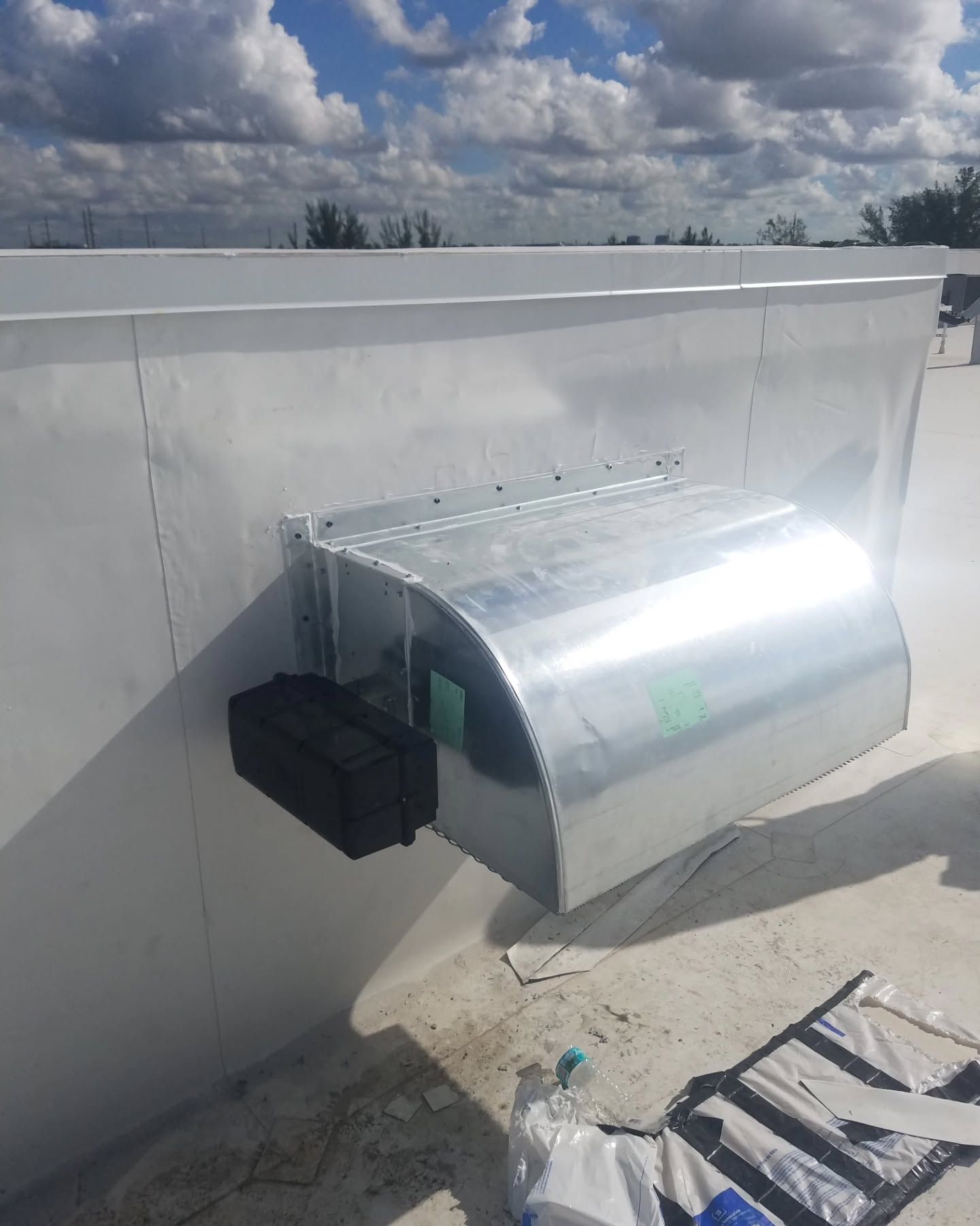 A large metal pipe is hanging from the side of a building.