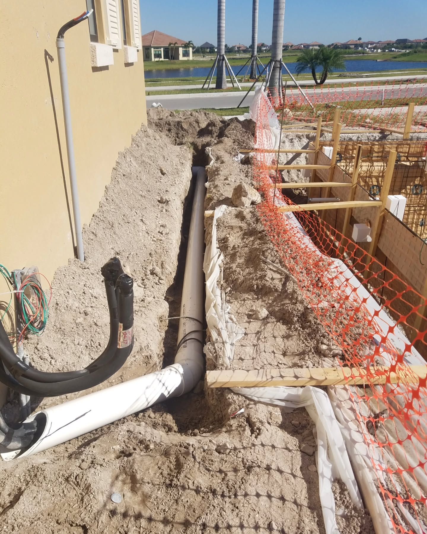 A pipe is being installed in the dirt next to a building.
