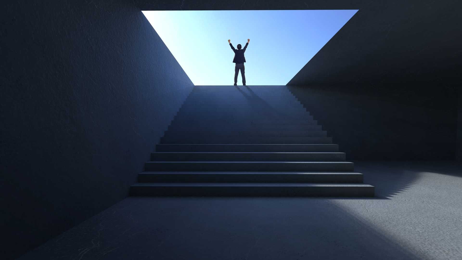 A man is standing on top of a set of stairs with his arms in the air.