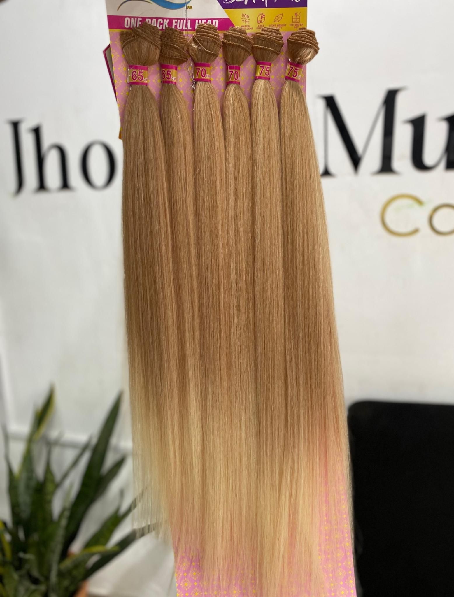 Un mechón de extensiones de cabello con efecto degradado de castaño claro a rubio, sostenido sobre un fondo blanco con el logotipo de la marca.