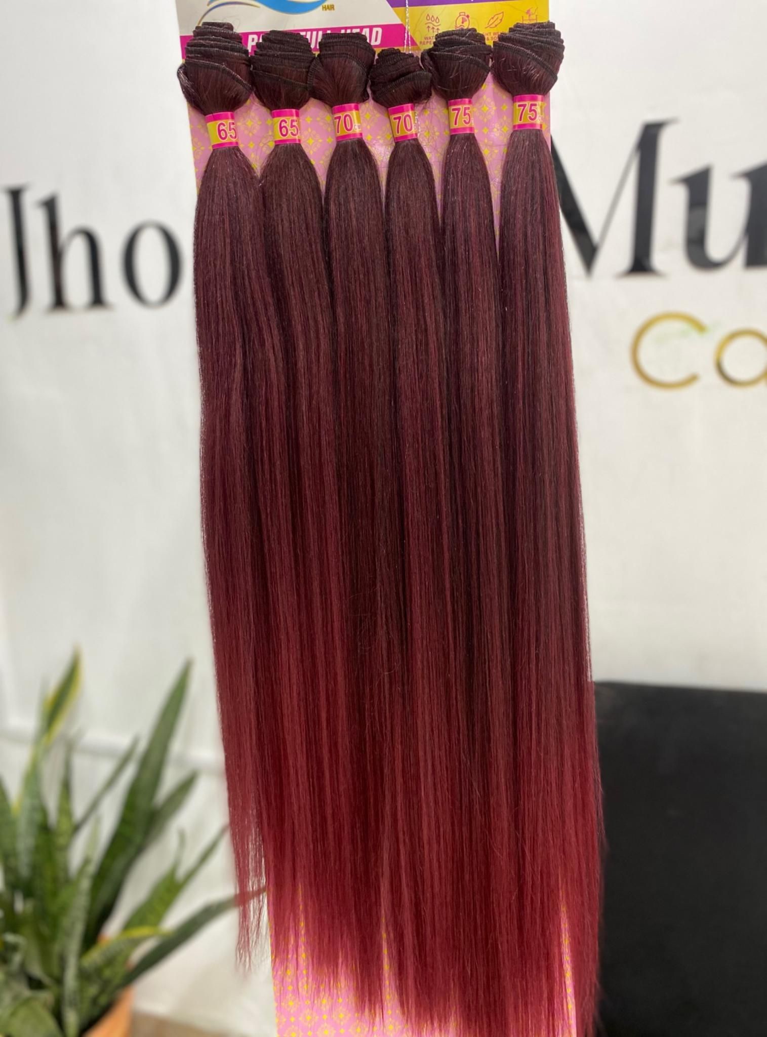 Un mechón de extensiones de cabello largo, de color rojo intenso y textura rizada, sostenido sobre un fondo blanco.
