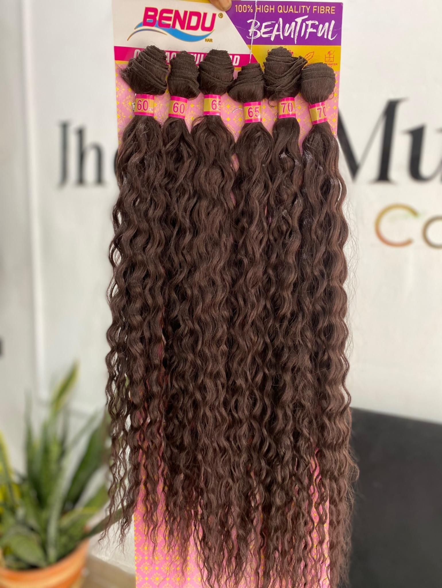 Un paquete de seis mechones de extensiones de cabello rizado de ganchillo de color marrón oscuro de la marca Bendu, mostrados sobre un fondo borroso.