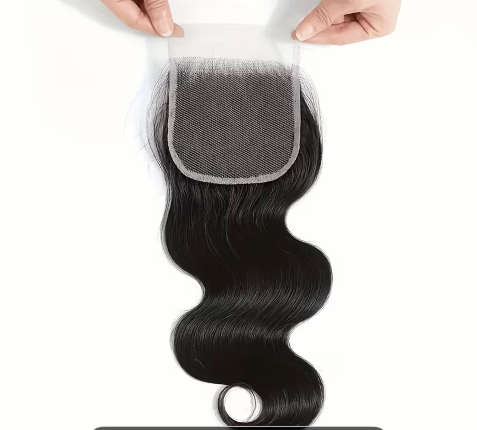 Manos que sostienen un cierre de encaje para cabello oscuro y ondulado sobre un fondo blanco liso.