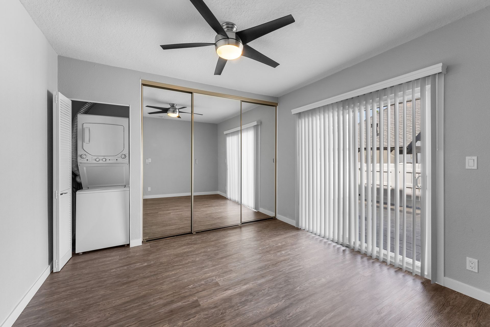 Bedroom with blinds, mirror closet and washer and dryer
