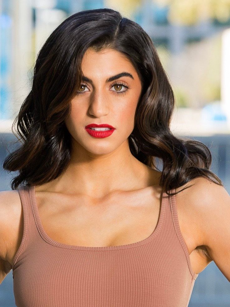 The woman is wearing a tank top and red lipstick.