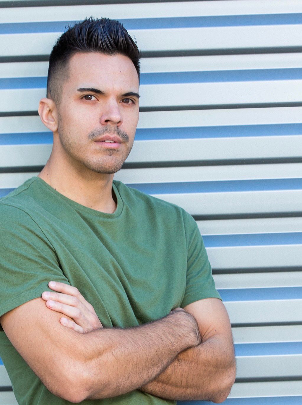 A man in a green shirt is standing with his arms crossed.