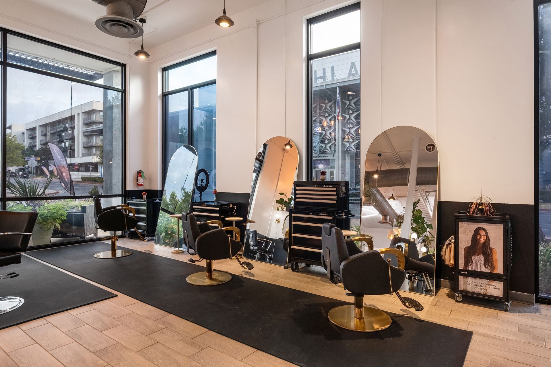 Hair salon interior with styling stations, mirrors, and large windows.