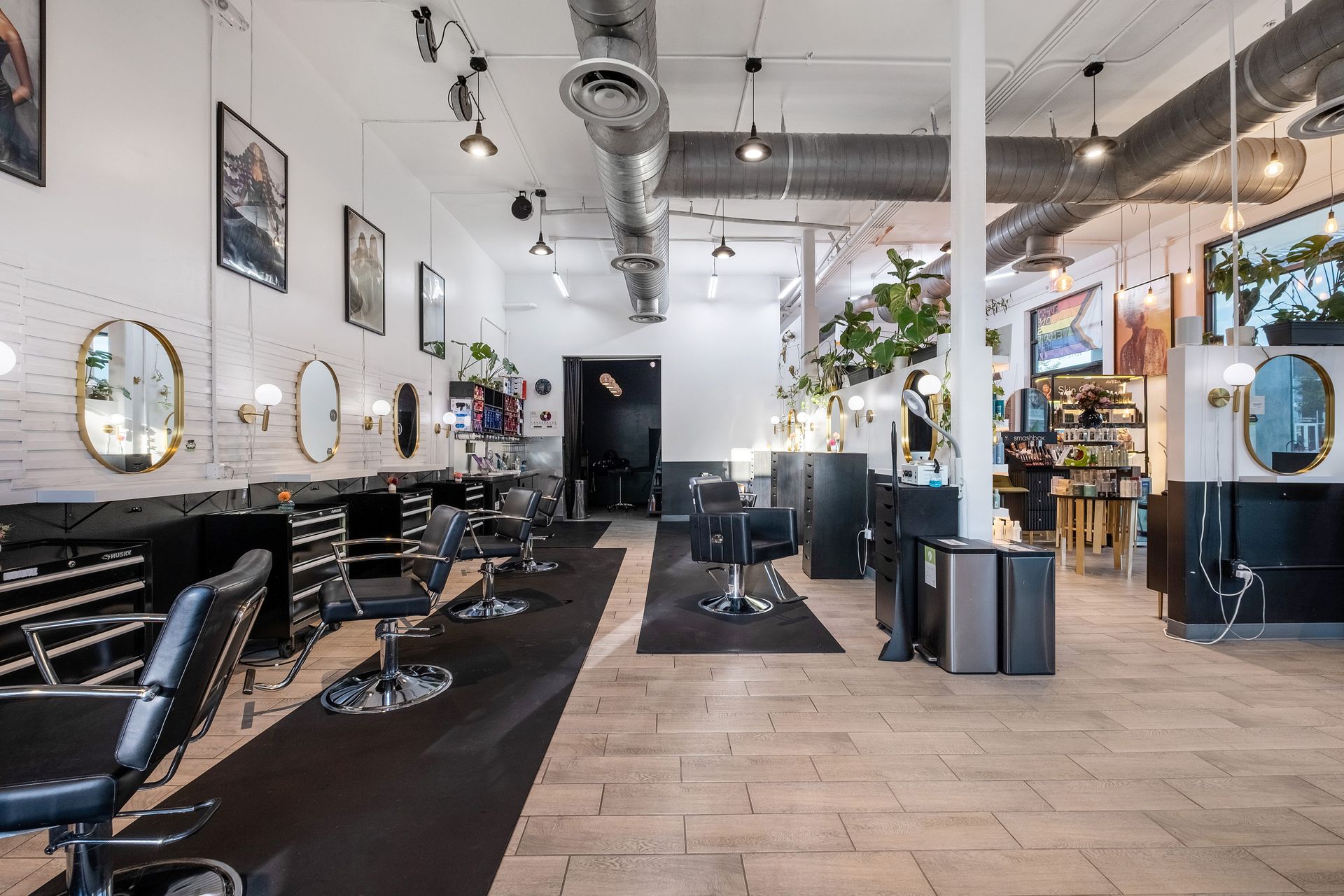 Interior of a modern hair salon with chairs, mirrors, and stylists' stations. White walls, black accents.